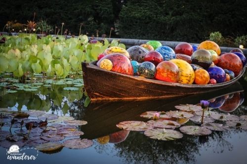 A boat floating in a pond filled with colorful glass orbs