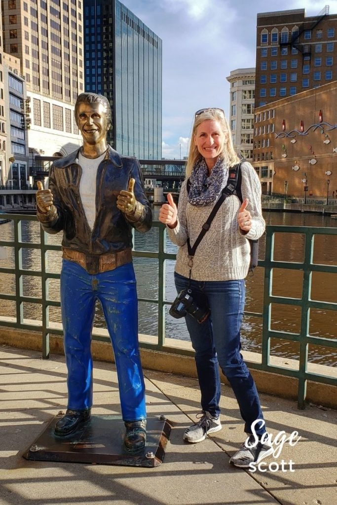 Sage Scott standing next to the Bronze Fonz statue on the Milwaukee riverwalk