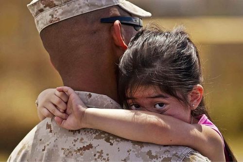 Girl hugging military dad in uniform
