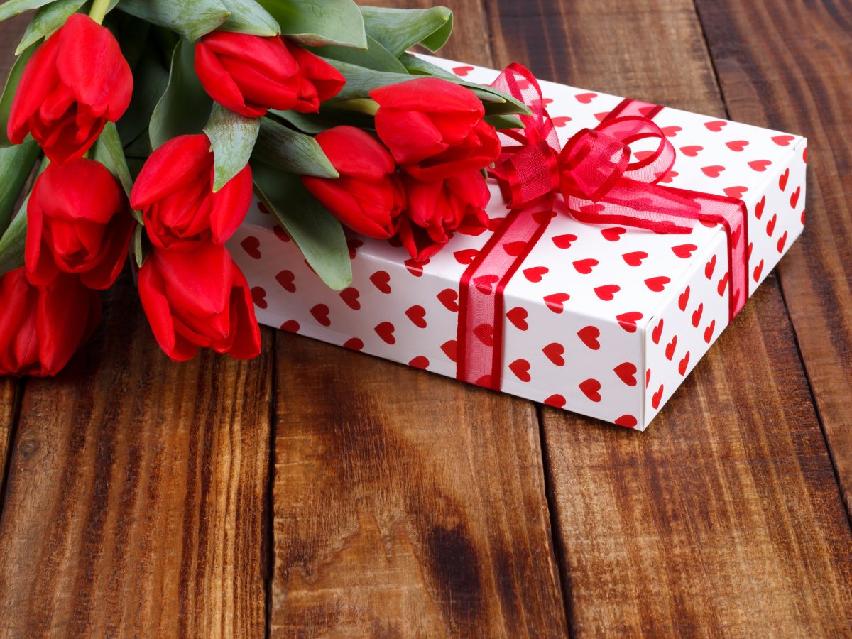 Bouquet of red tulips with a gift wrapped in red heart paper