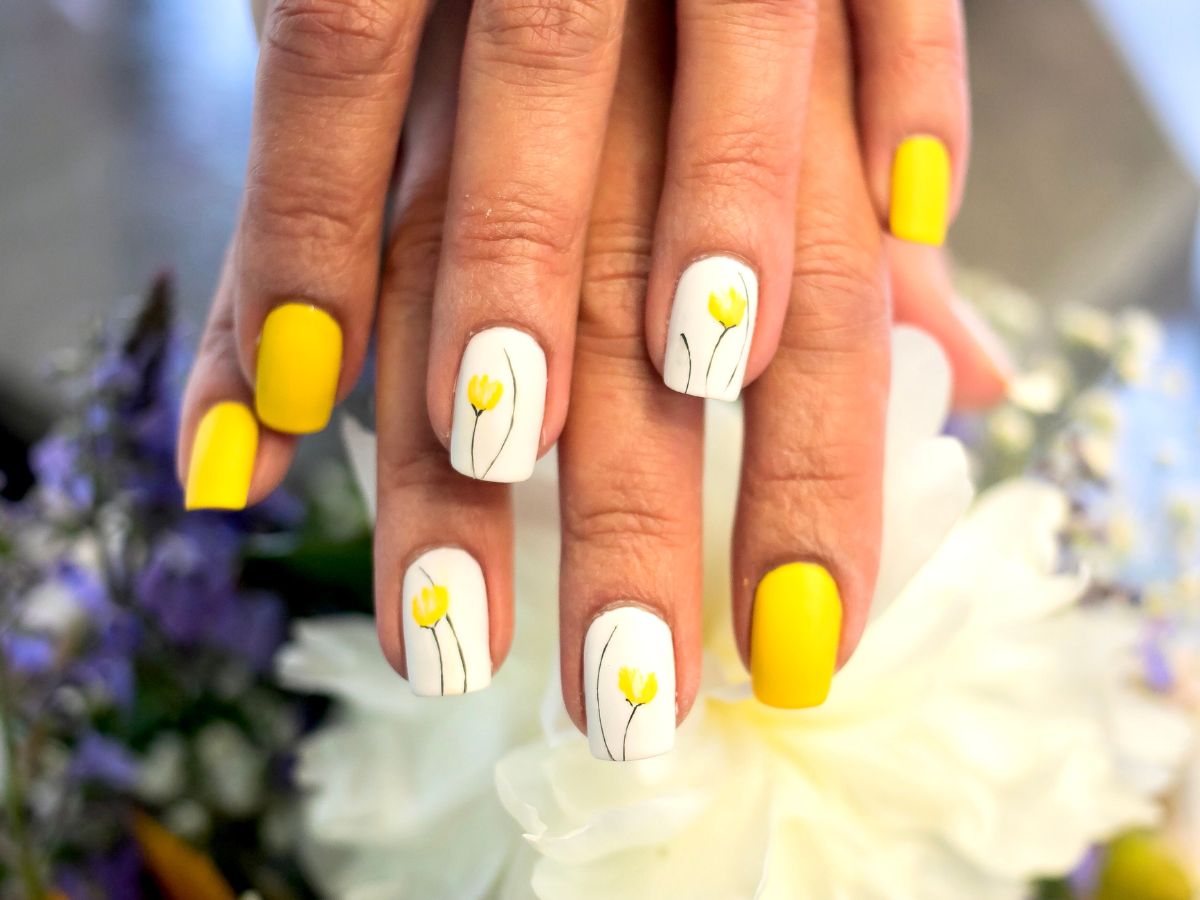 Tulip nail design with yellow and white fingernail polish.